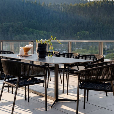 Close Up View Of The Afton Outdoor Dining Chair With Black Cord And Black Frame On A Patio Next to a Black Table