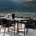 Close Up View Of The Afton Outdoor Dining Chair With Black Cord And Black Frame On A Patio Next to a Black Table