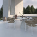 Four Afton Outdoor Dining Chairs With Natural Cord And White Frame On A Patio Next to a White Table
