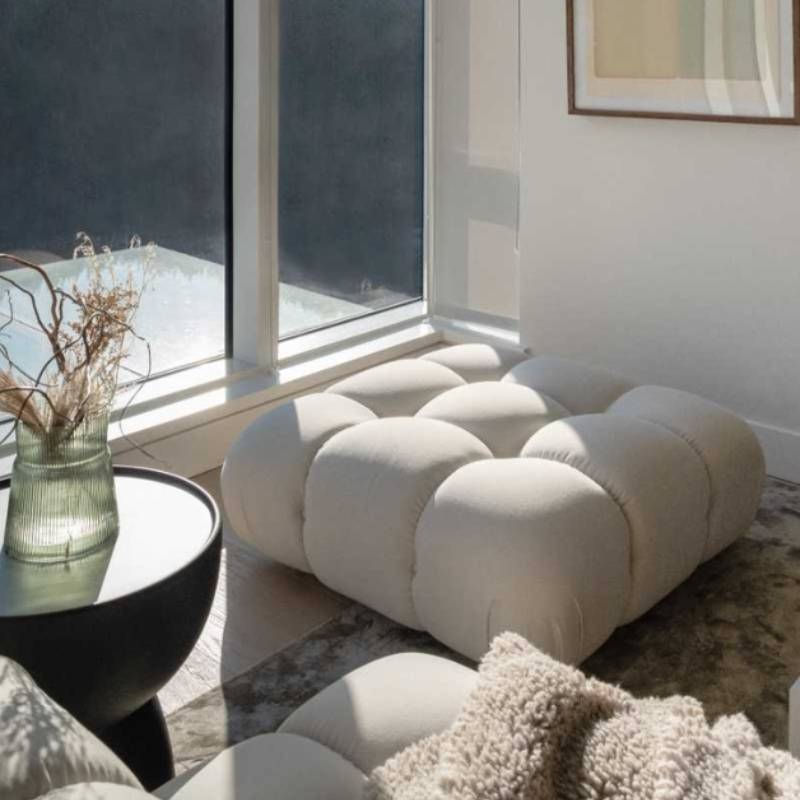 The Belia Ottoman Modular Sectional Piece With Alesund Fabric in The Corner of a Living Room