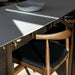 Sun Shining of a portion of a Table and an Elbow Chair in Trento Jet Black and Wood Finishes