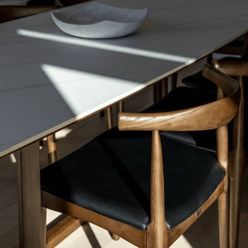 Sun Shining of a portion of a Table and an Elbow Chair in Trento Jet Black and Wood Finishes