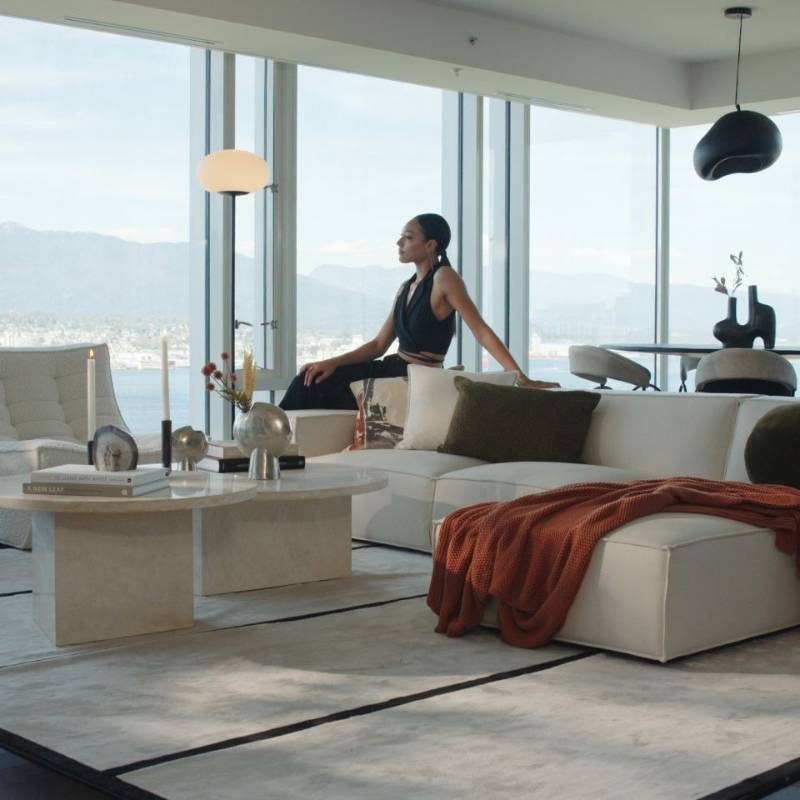 Woman Stitting on a Couch Next to The Romulus Nesting Coffee Table in White Travertine