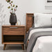 The Asher Single Drawer Nightstand With Walnut Veneer Finish on The Left Side of a Bed
