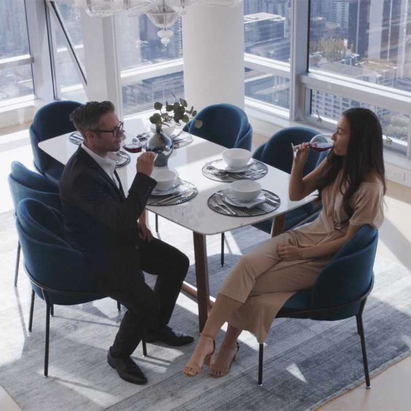 Couple Sitting at the Evelyn Dining Table in White Carrara Marble in The Corner of a Dining Area Overlooking a City View