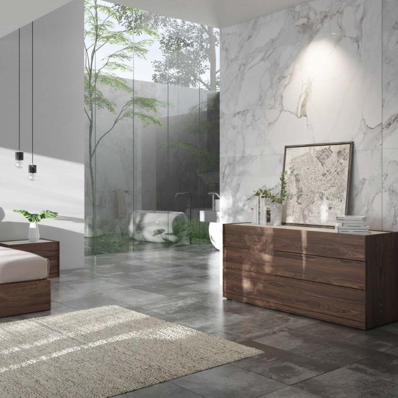 The Hunter Wide Dresser in a Walnut Veneer Finish Next Against a Marble Bedroom Wall With Bathroom in The Background