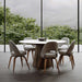 Front Facing View of The Winston Dining Table 63 inch in White Calacatta Ceramic Surface and Walnut Veneer Base in Dining Room Next to Large Window