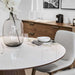 Close Up View of The Winston Dining Table 48 Inch With High Gloss White Lacquer Surface and Walnut Veneer Finish With Cabinet in the Background